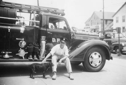 July 15, 1954 - Chan Brainard on running board of Engine 4 with Station 4 mascot "Blackie"